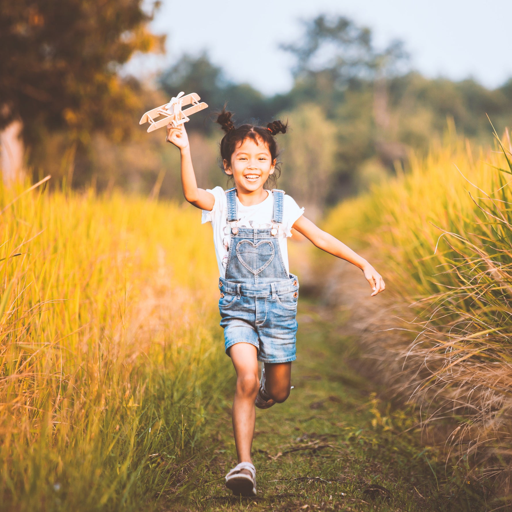 Child running down a path in a field with tall grass