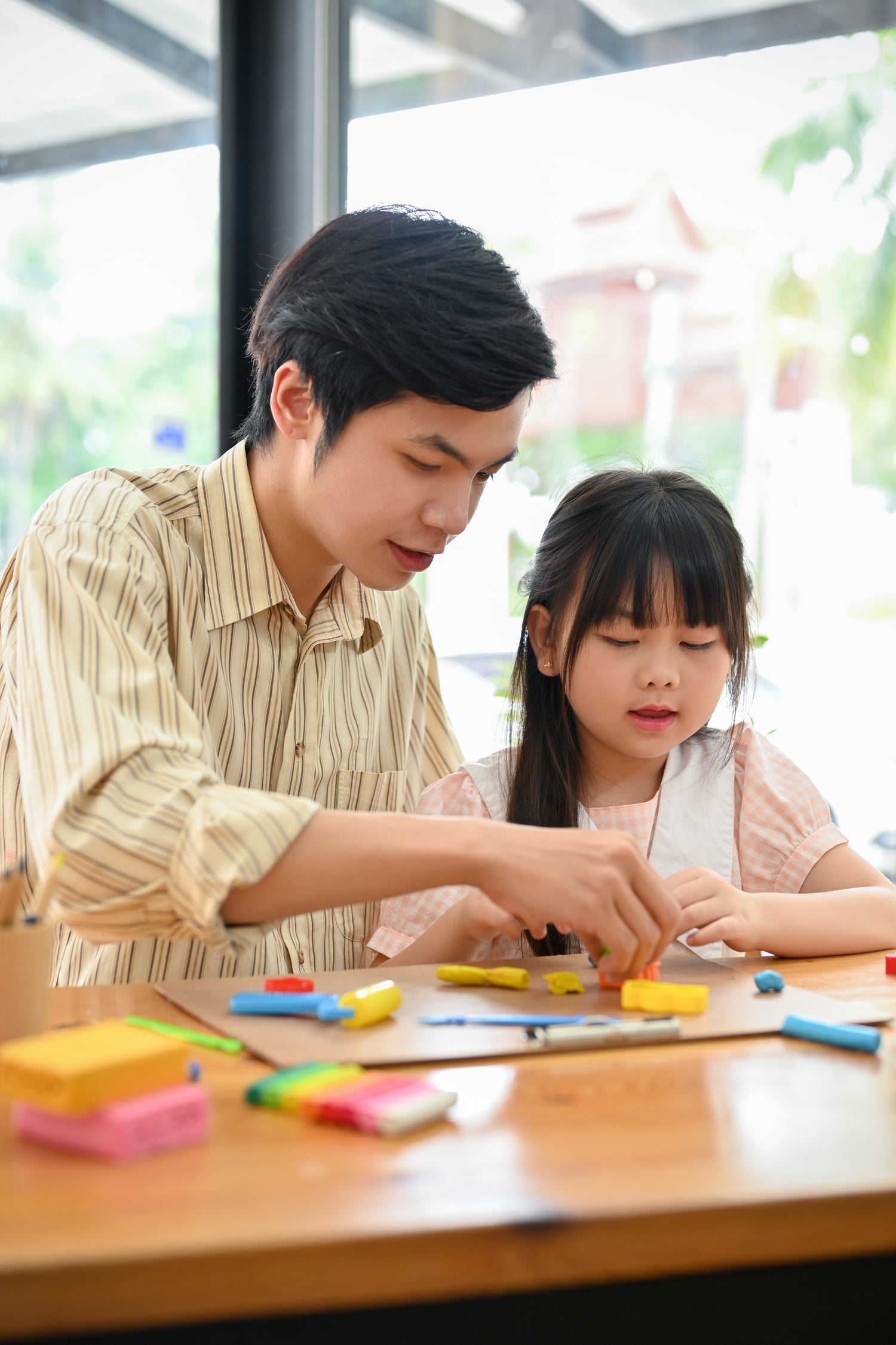 Man and young girl engaged in an activity with colorful items at a table.