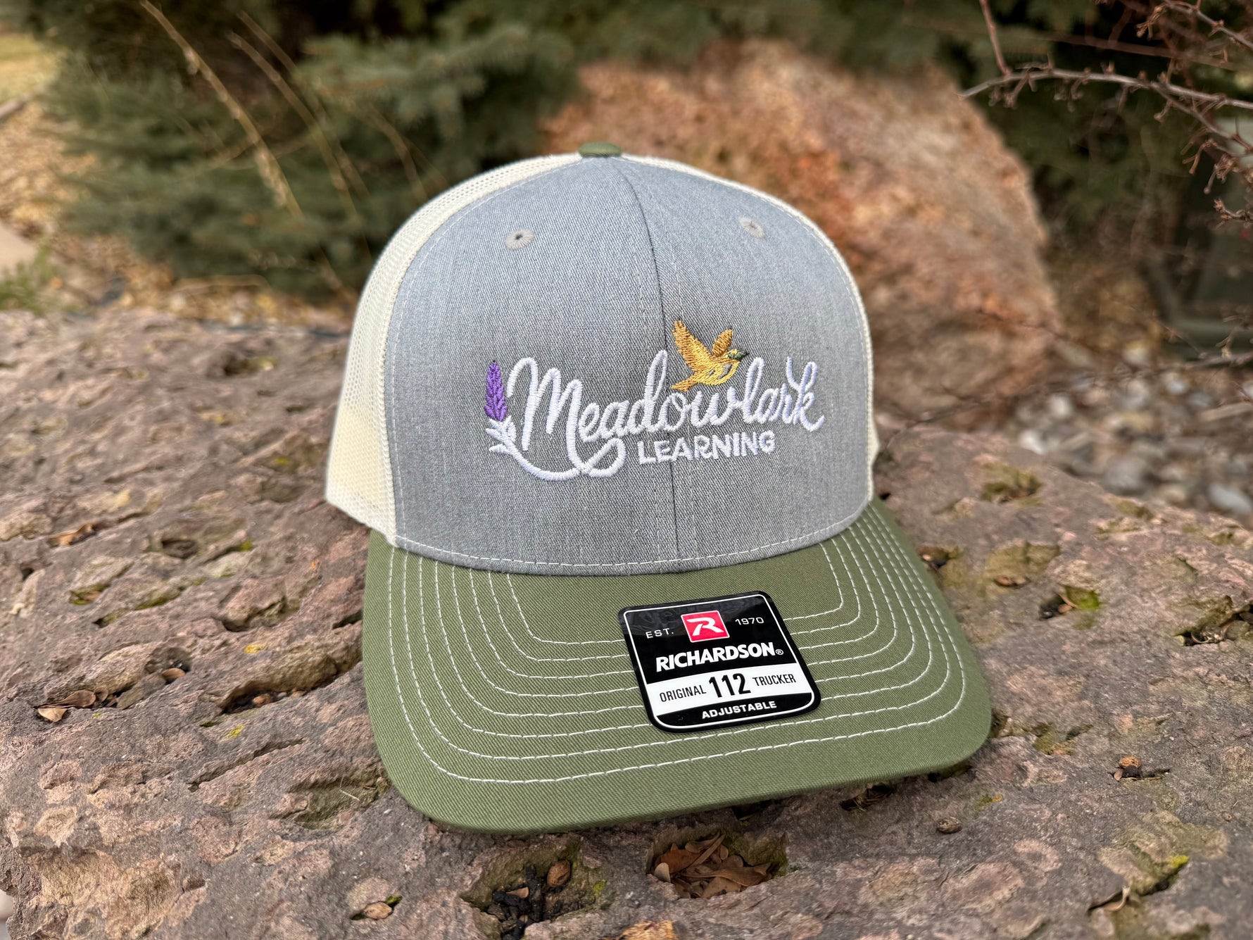 Gray and green cap with 'Meadowlark Learning' logo on a stone surface