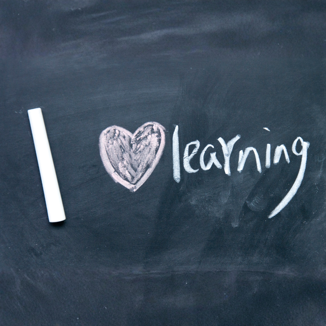 Blackboard with 'I ❤️ learning' written on it, accompanied by a piece of chalk.