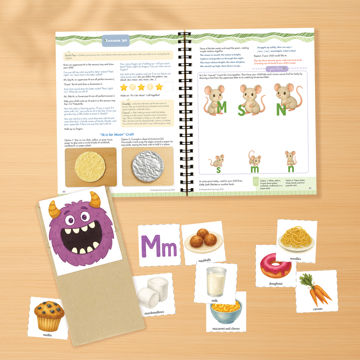 Educational materials including a book, flashcards, and cards on a wooden surface